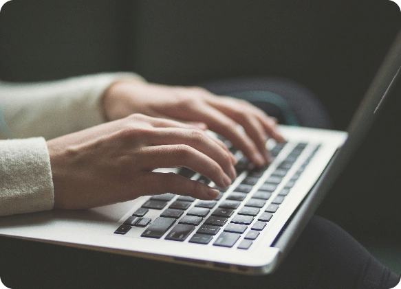 close up of hands typing on a silver laptop keyboard